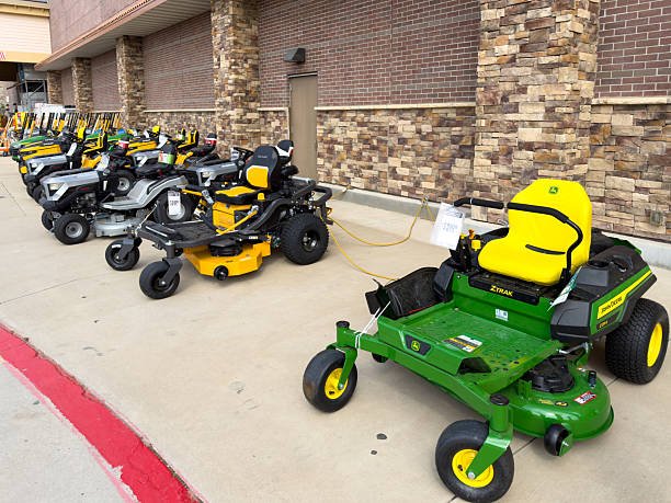 Prosper, Texas, USA - April 1st, 2026: Green John Deere Z315E ZTrak and yellow Cub Cadet Ultima zero-turn lawn mowers sitting on concrete display area in The Home Depot